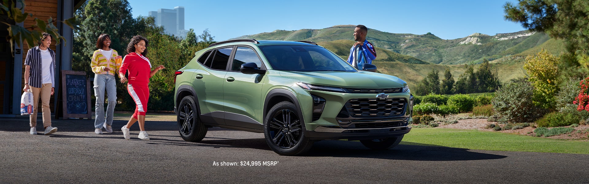 A green Chevrolet Trax parked outdoors with four people walking nearby
