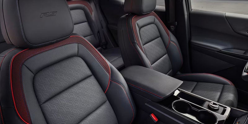 Interior view of black leather car seats with red stitching.