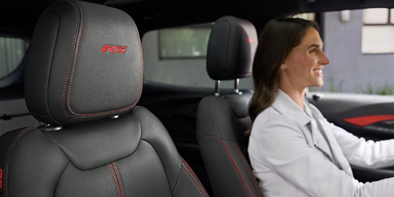 Close-up of black leather car seats with red stitching.